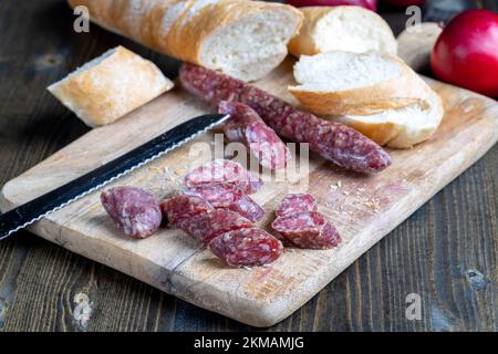 i pezzi di salsiccia affettati di carne sono sdraiati su un tagliere, la carne di maiale con la pancetta è secca e appassita, la carne è pronta per mangiare Foto Stock