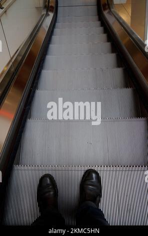 Piedi di un uomo su una scala mobile, che scende. Non c'è nessun altro. La foto viene fatta in un grande centro commerciale di Leverkusen, Germania Foto Stock