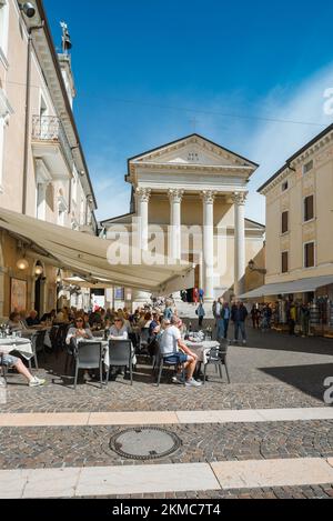 Bardolino città Lago di Garda, vista in estate di persone che si rilassano ai tavoli da caffè in Via San Martino, nel centro storico di Bardolino, Italia Foto Stock