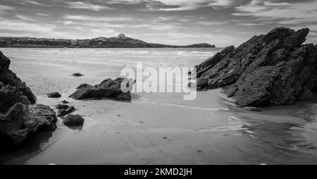 Rocce nella sabbia di Towan Beach con vista sul porto, il promontorio e il centro di Newquay sullo sfondo Foto Stock