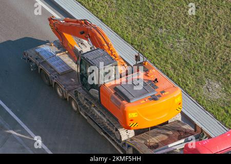 Autocarro con una lunga piattaforma per rimorchio per il trasporto di macchinari pesanti, escavatore caricato. Trasporto su autostrada Foto Stock