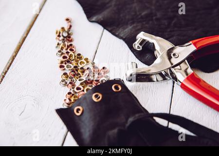 Pinze per occhielli con piccolo occhielli in metallo di vari colori concetto di utensili per la casa. Foto Stock