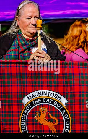 Una donna detiene un tartan che rappresenta il clan Mackintosh durante la sfilata di tartan al Scottish Highland Games di Gulfport, Mississippi. Foto Stock