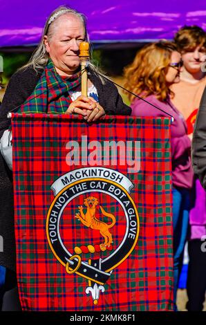 Una donna detiene un tartan che rappresenta il clan Mackintosh durante la sfilata di tartan al Scottish Highland Games di Gulfport, Mississippi. Foto Stock