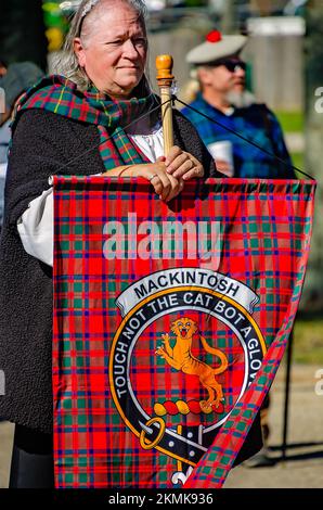 Una donna detiene un tartan che rappresenta il clan Mackintosh durante la sfilata di tartan al Scottish Highland Games di Gulfport, Mississippi. Foto Stock