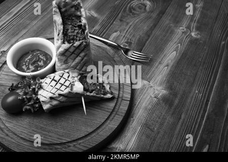 Carne tritata avvolta con pane di lavash su sfondo di legno. Foto Stock