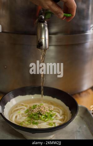 Il brodo Hot Dashi è atmicamente self-service a Hyogo Udon. Foto Stock