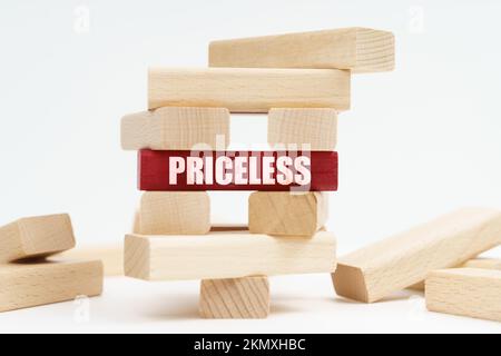 Concetto di business e finanza. Sulla superficie bianca si trova una torre di legno distrutta fatta di tavole, sulla lastra rossa si trova un'iscrizione - Pricel Foto Stock