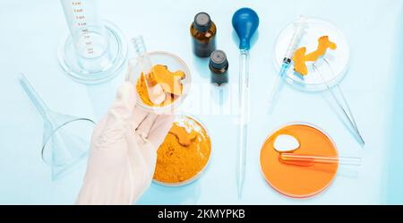 Ricerca medica delle proprietà curcuma con l'aiuto di attrezzature di laboratorio, donna in guanti di prova curcuma polvere. Vista dall'alto. Foto Stock