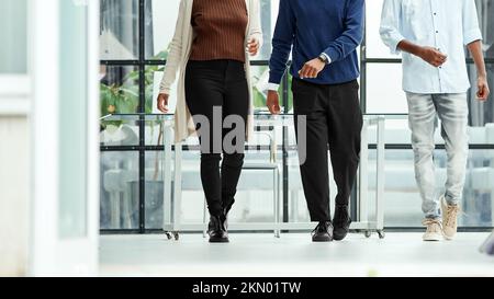 foto ritagliata delle gambe che camminano fino alla vita. gruppo di giovani uomini d'affari che attraversano una sala ufficio. copia dello spazio di testo Foto Stock