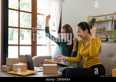 Due giovani donne asiatiche sono felici ed eccitati dopo un nuovo ordine da SME cliente, controllo commerciale, marketing online, imprenditorialità confezioni Foto Stock