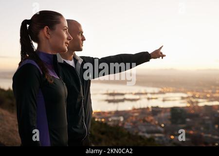 Dedicato al fitness e l'uno all'altro. un giovane sportivo che indica la vista alla sua ragazza. Foto Stock