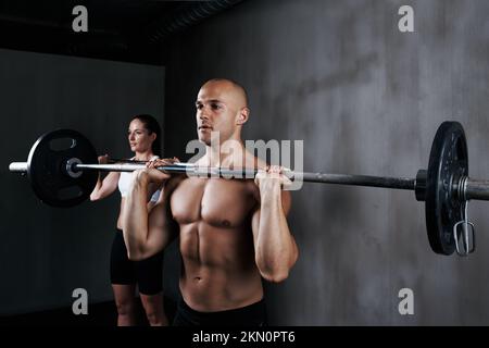 Allenarsi per diventare in forma di combattimento. due persone che sollevano le campane durante un allenamento in palestra. Foto Stock