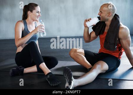 Allenarsi per diventare in forma di combattimento. un uomo e una donna che si prendono una pausa dopo un allenamento in palestra. Foto Stock