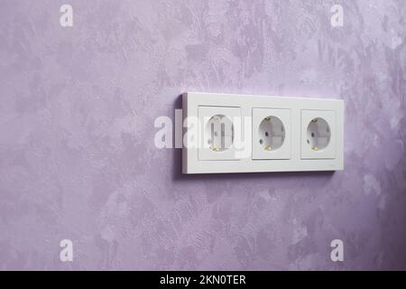 Presa a muro e parete viola. Dopo la riparazione. Profondità di campo poco profonda Foto Stock