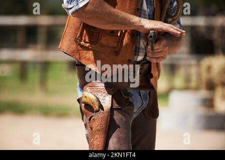 Un fuorilegge con un rapido sorteggio. un cowboy irriconoscibile con la sua pistola disegnata. Foto Stock