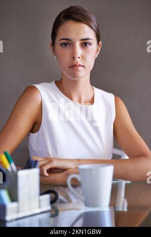 Prendendo sul serio il suo lavoro. Splendida donna d'affari seduta alla sua scrivania. Foto Stock