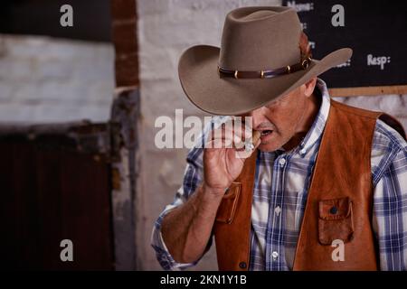 Tempo di bussare per il cowboy. un cowboy anziano che gode un sigaro sul suo ranch. Foto Stock