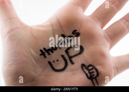 Pollici su scritto sul palmo della mano su uno sfondo bianco Foto Stock