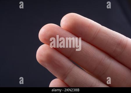 Tre dita di una mano del bambino in parte visibile in sfondo nero Foto Stock