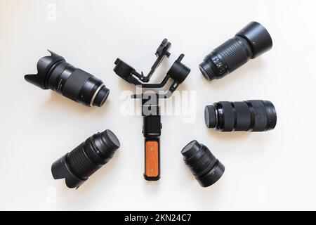 Vista dall'alto del videografo dello spazio di lavoro con attrezzatura digitale, stabilizzatore di gimbal, obiettivo e accessorio fotocamera su sfondo bianco del tavolo Foto Stock