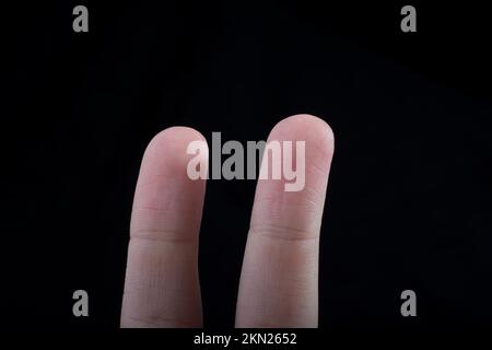 Due dita di una mano del bambino in parte visibile in sfondo nero Foto Stock