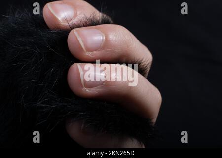 Tre dita di una mano del bambino in parte visibile in sfondo nero Foto Stock