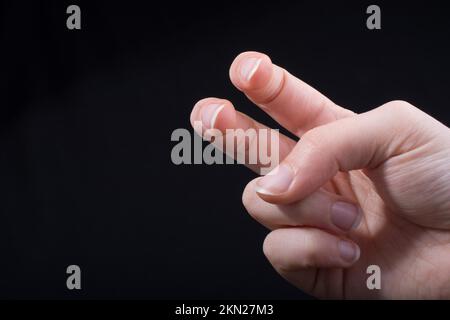 Due dita di una mano del bambino in parte visibile in sfondo nero Foto Stock