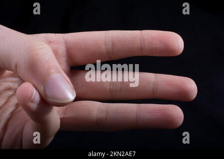 Tre dita di una mano del bambino in parte visibile in sfondo nero Foto Stock