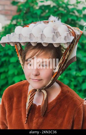 Ragazza adolescente con uova e pulcino sulla testa Foto Stock