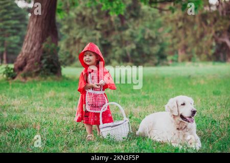 bambino in un costume da equitazione rosso e golden retriever al posto del lupo Foto Stock