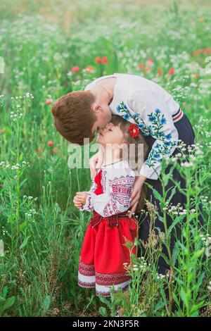 Mamma in ucraino abito nazionale bacia sua figlia in un fiore Foto Stock