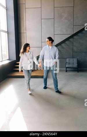 giovane coppia felice uomo e donna in piedi nei loro nuovi appartamenti accoglienti dopo un bene immobile di successo Foto Stock