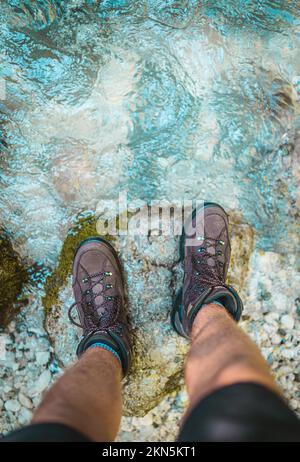 Un colpo ad angolo alto di un mans piedi con scarpe marroni che si stancavano sulla riva Foto Stock