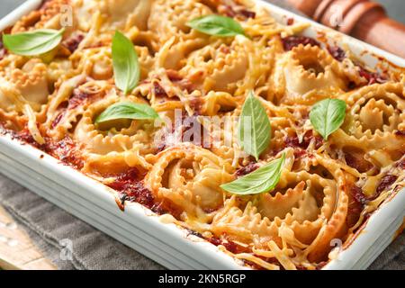 Lasagne. Lasagne fatte in casa - rotolo di pasta cuocere con salsa di pomodoro, crema di formaggio e basilico su padella bianca su fondo di ardesia scura, pietra o cemento. Esso Foto Stock