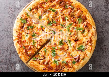 Pollo pizza barbecue a pezzi di pollo con salsa piccante con condimenti di cipolle, mozzarella e coilantro sul bordo di legno Foto Stock