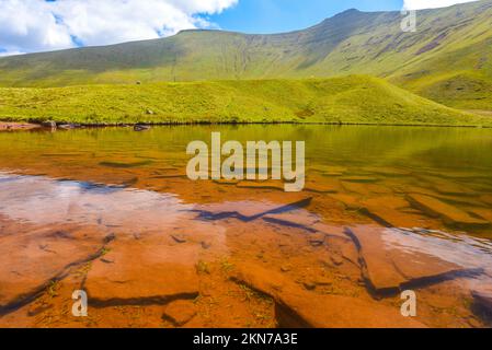 Acque incredibilmente limpide del lago Llyn CWM Llwch con Pen-Y-Fan sullo sfondo, Brecon Beacons National Park. Foto Stock