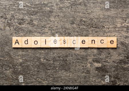 parola adolescenza scritta su blocco di legno. testo adolescente sulla tabella, concetto. Foto Stock