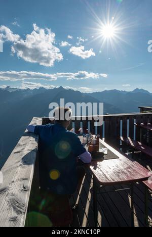 Un escursionista si trova sulla terrazza del rifugio Brunnenkogelhaus e si affaccia sul panorama delle Alpi di Ötztal e della Valle di Gurgl, Tirolo, Austria Foto Stock