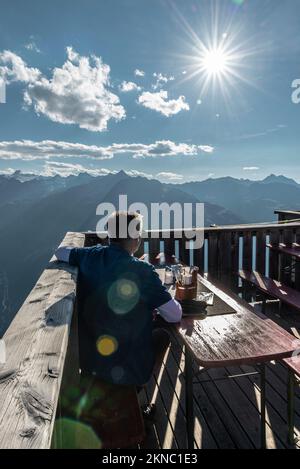 Un escursionista si trova sulla terrazza del rifugio Brunnenkogelhaus e si affaccia sul panorama delle Alpi di Ötztal e della Valle di Gurgl, Tirolo, Austria Foto Stock