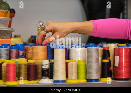 Fasciatoio irriconoscibile con abiti colorati che scelgono un filo. Foto Stock