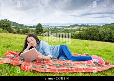 Donna sdraiata e rilassante in un campo erboso Foto Stock