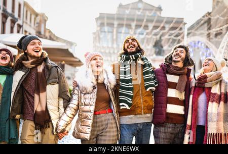 Felice gruppo di studenti a piedi in città europea il giorno di sole inverno - Next gen z concetto di stile di vita con i giovani multirazziali indossare abiti caldi Foto Stock