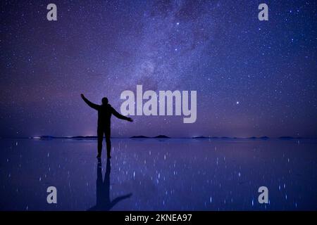 Cielo stellare notturno a Uyuni Salt Flats, Bolivia, con una persona di silhouette in piedi sulla superficie riflettente. Foto Stock