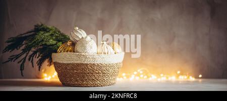 Ramo dell'albero di Natale e baubles in cesto intrecciato con luci bokeh di Natale sullo sfondo Foto Stock