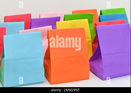 Set di colorati sacchetti di carta piegati shopping su sfondo bianco. Borse della spesa in carta mockup, confezioni regalo rettangolari vuote. Mock up per marchio e logo. Foto Stock
