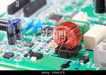 Bobina di rame o bobina di induttanza sulla scheda a circuito stampato, componenti elettronici all'interno del computer. Foto Stock