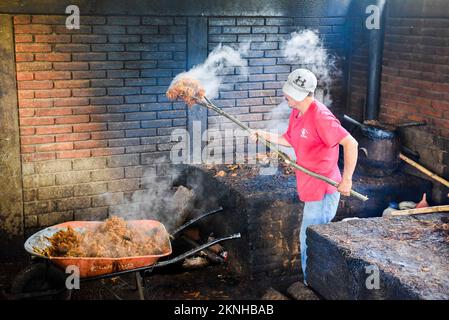 Dopo il primo processo di distillazione dei cuori di agave schiacciati, la purea calda viene rimossa manualmente , distilleria artigianale Mezcal , Oaxaca Mexico Foto Stock