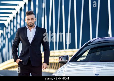 un uomo bianco in una tuta vicino ad una macchina bianca guarda nel telaio. Foto Stock