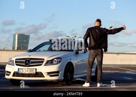 27,10,2022, Polonia. Un ragazzo in una Mercedes tiene la mano a lato e punta i pollici su e giù Foto Stock
